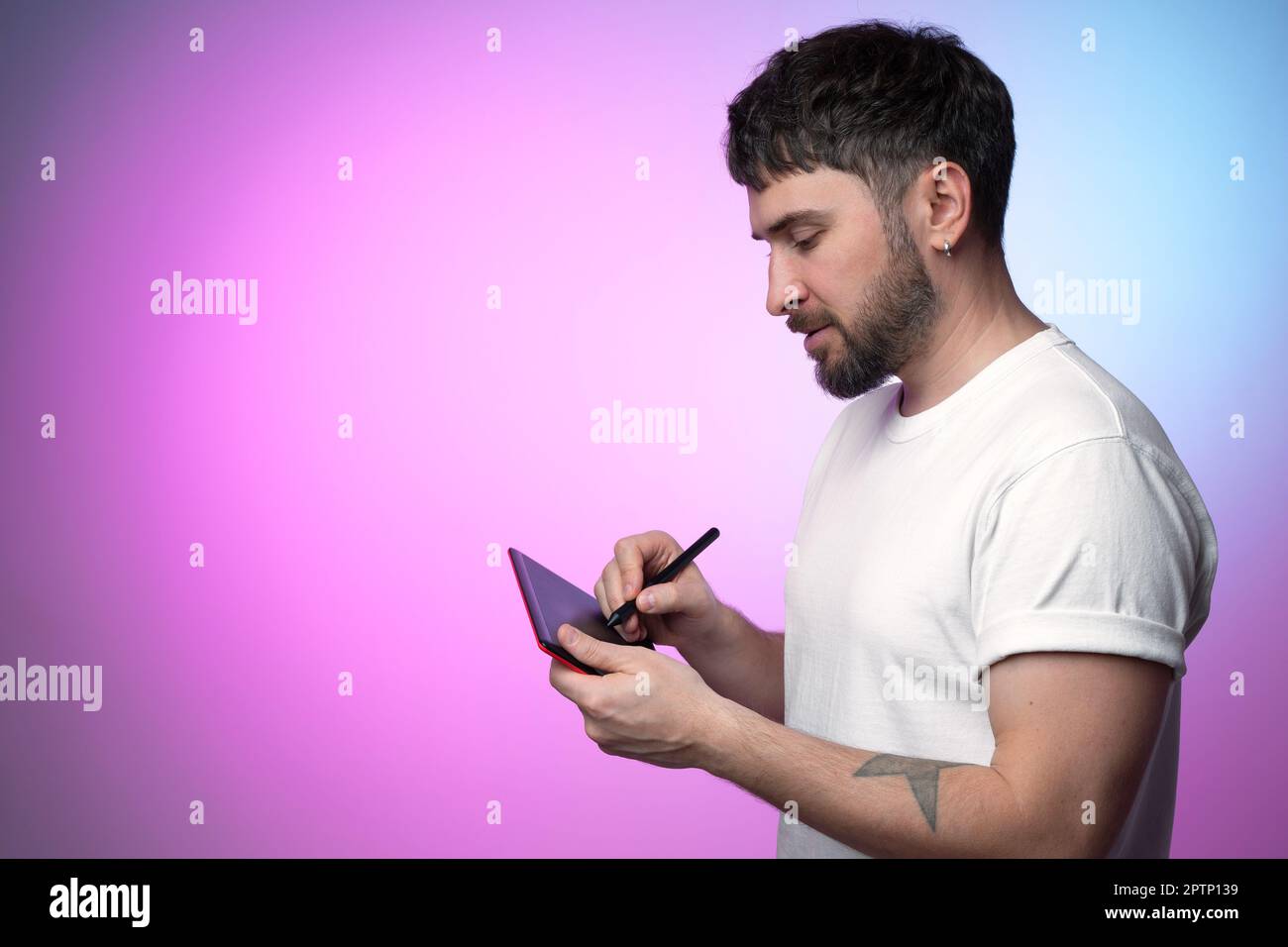 L'artista digitale crea un token NFT non fungibile per la cripto-arte in blockchain. Disegna utilizzando un tablet grafico. Uomo bearded in t-shirt bianca crea Foto Stock