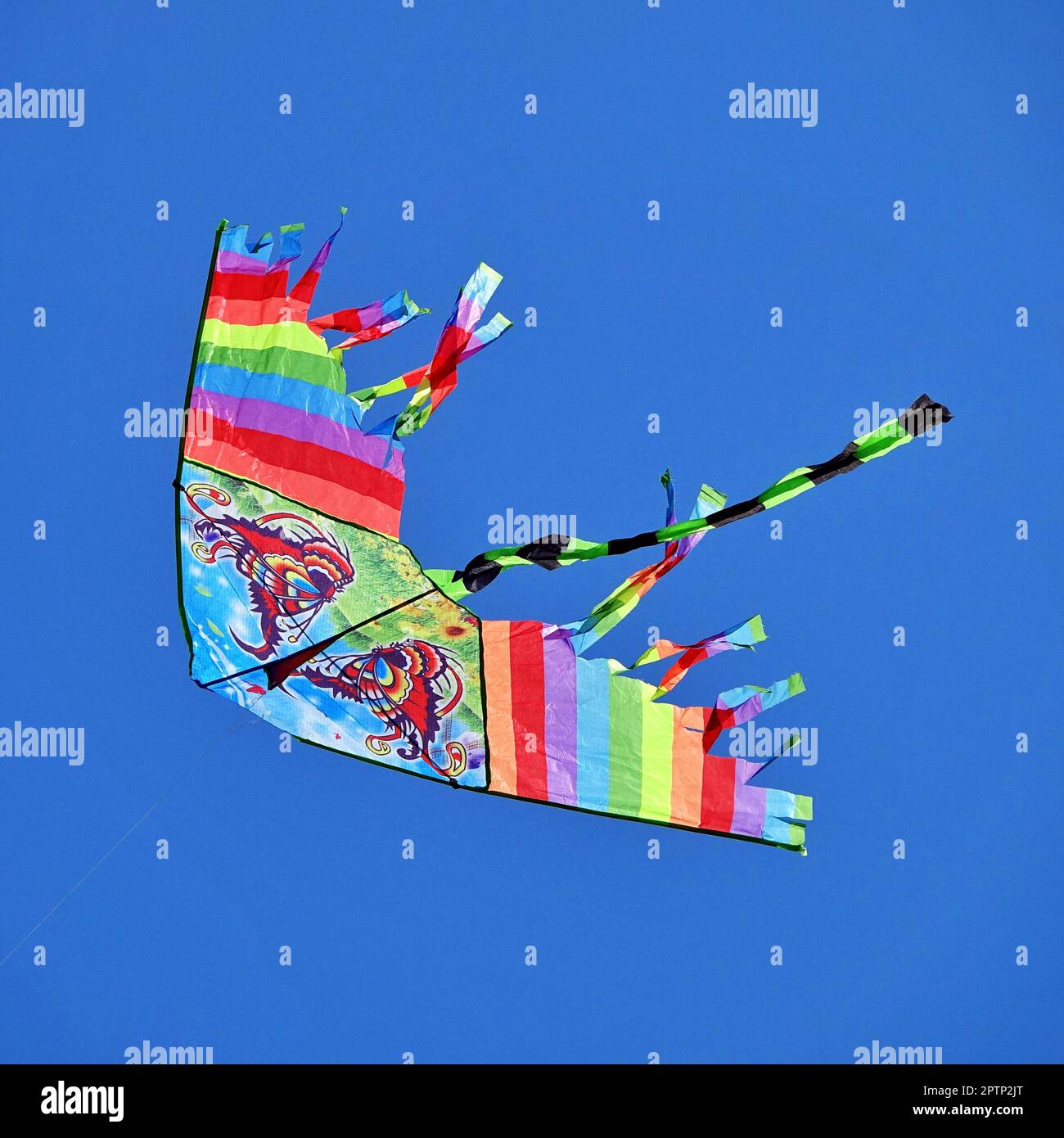 Un unico aquilone fai-da-te multicolore di colore arcobaleno fatto a mano vola isolato nel cielo blu. Concetto di libertà Foto Stock