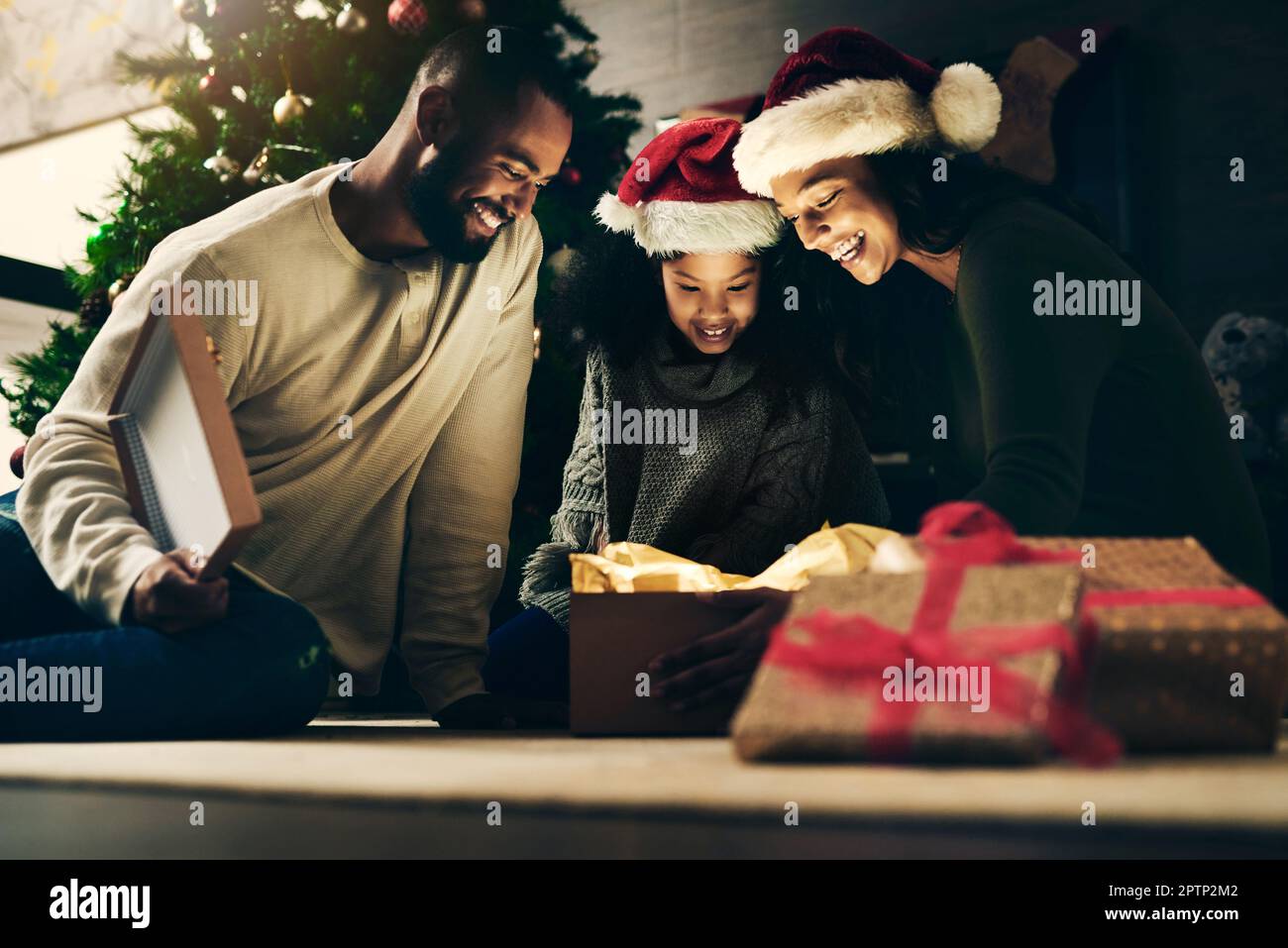 Madre, padre e bambino con dono per Natale in celebrazione di una vacanza cristiana invernale come una famiglia felice. Notte, mamma e papà amano dare i giovani Foto Stock