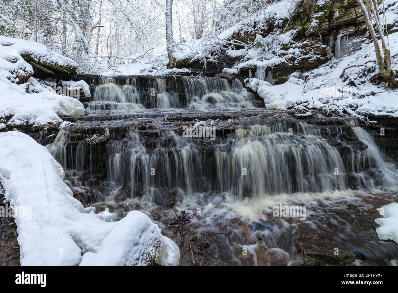Piccola cascata Vasaristi in inverno, parco nazionale di Lahemaa, Estonia. Esposizione lunga Foto Stock