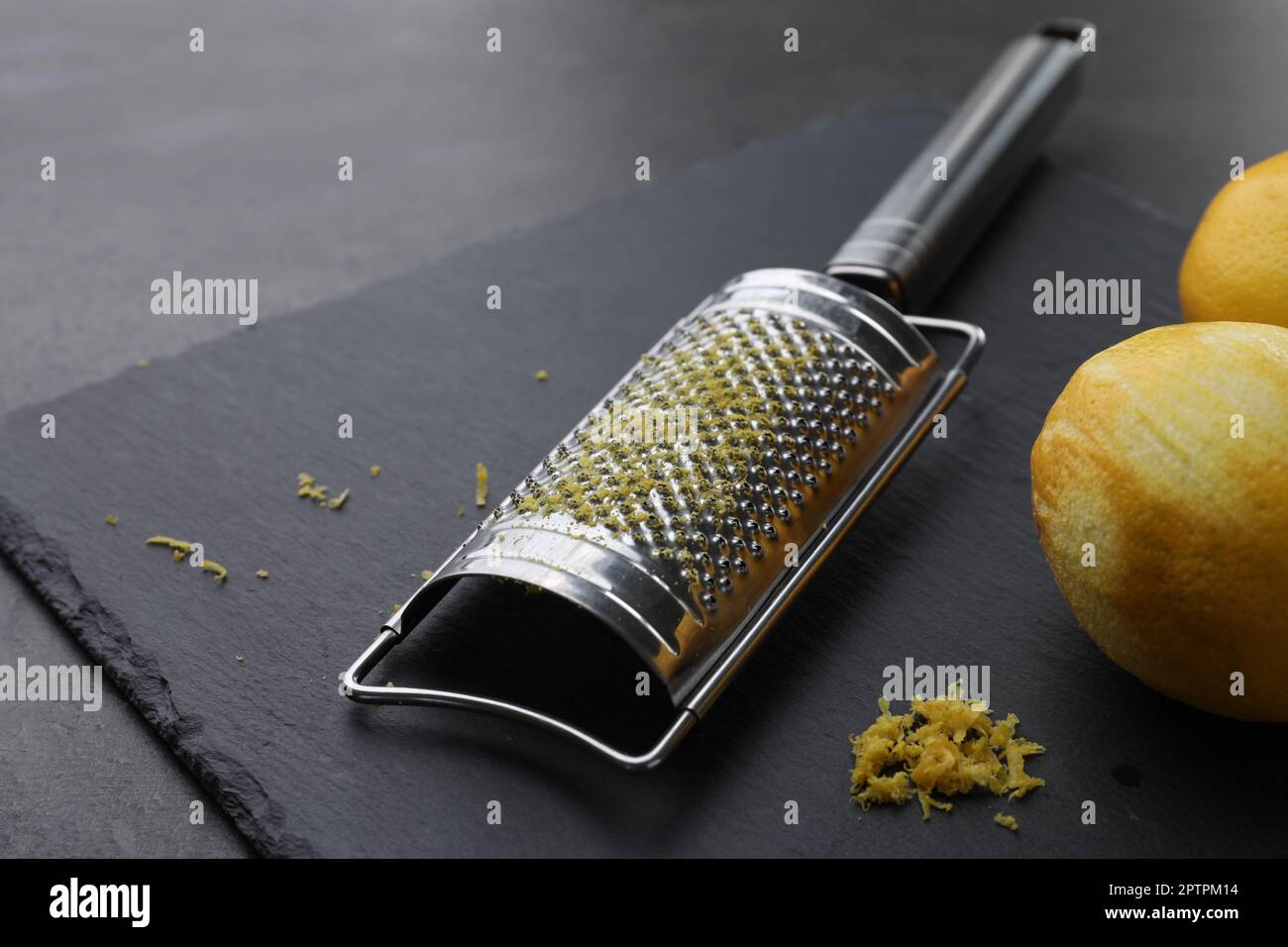 Grattugia e limoni freschi su tavola nera Foto stock - Alamy