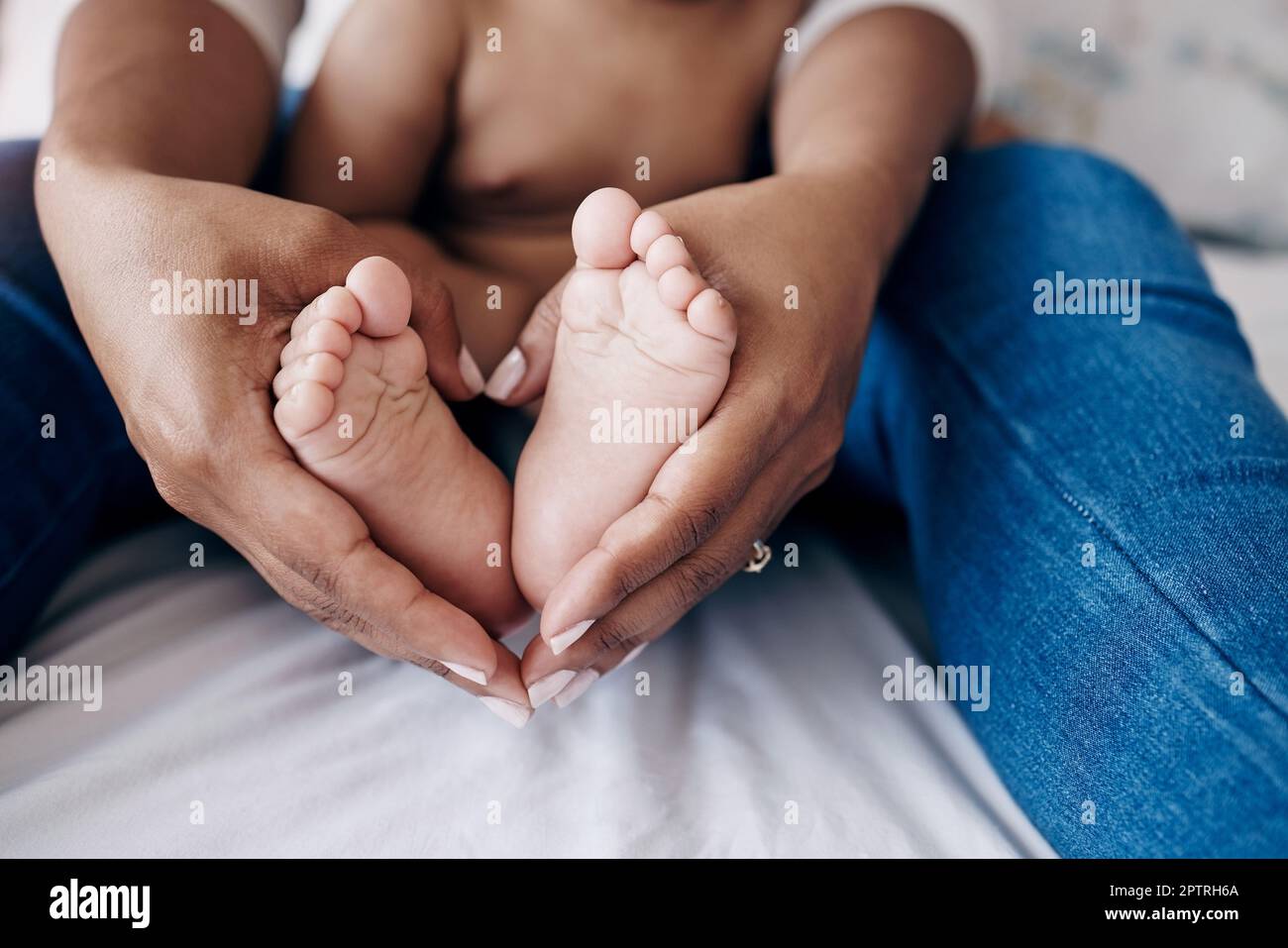 Creare momenti indimenticabili. una donna irriconoscibile seduta sul letto  a casa e che tiene i piedi delle sue bambine Foto stock - Alamy
