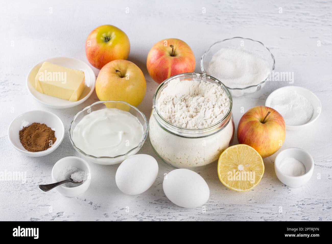 Ingredienti per cheesecake fatti in casa o torta di mele: Mele, farina, panna acida o yogurt, burro, zucchero, uova, lievito in polvere, limone, cannella e sale o Foto Stock