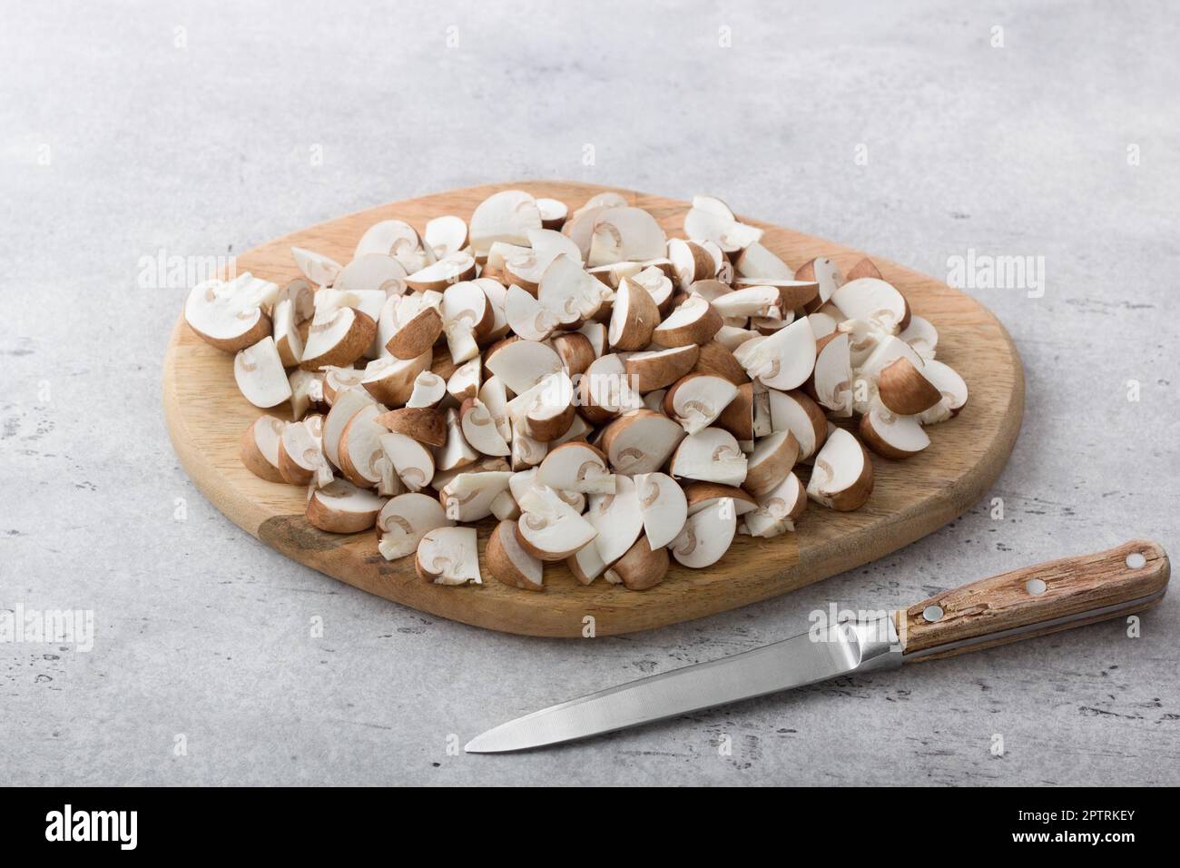 Tavola di legno con champignons castani tritati per la cottura а piatto vegano Foto Stock