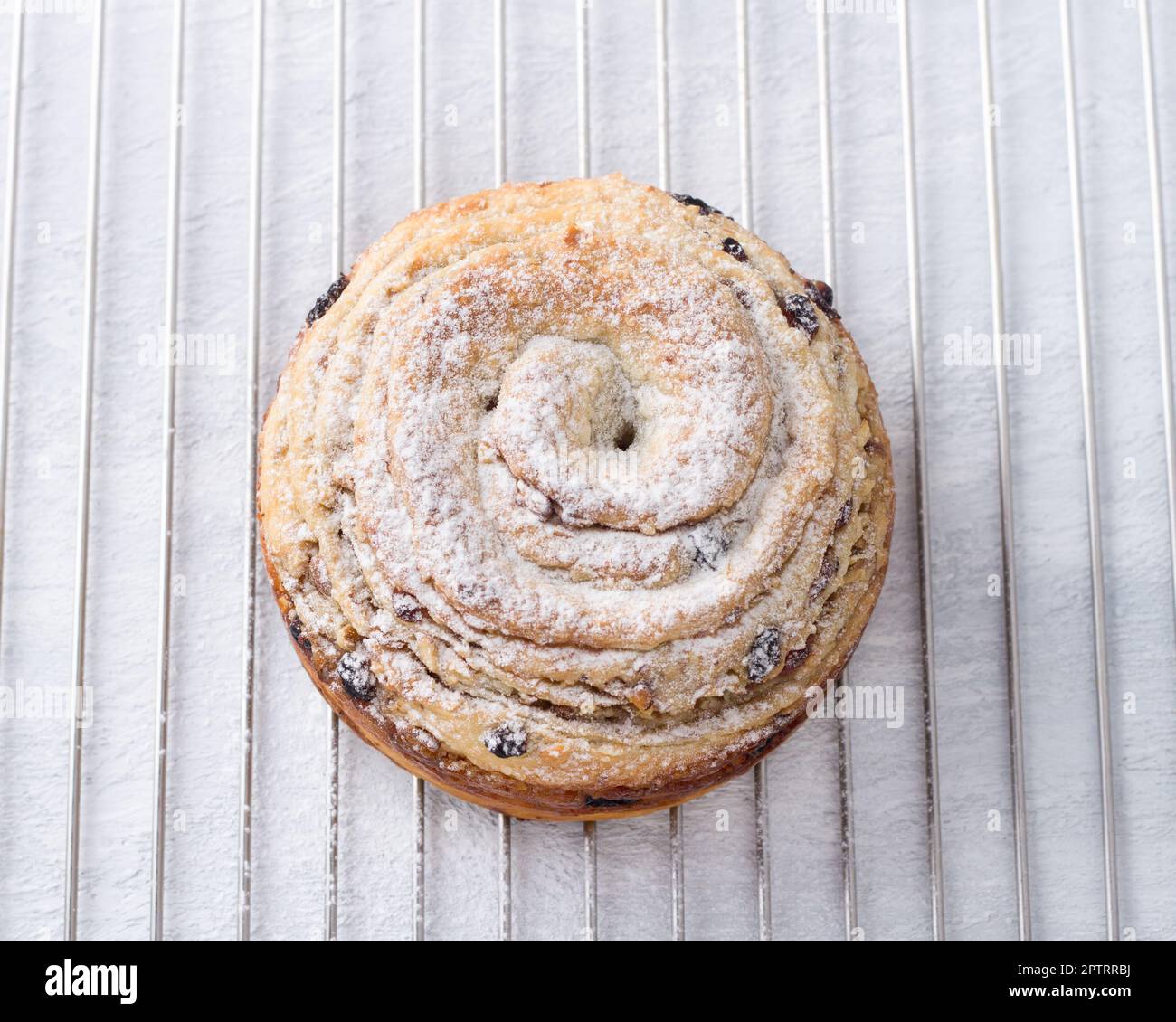 Boccetta fatta in casa - cruffin con noci e frutta secca, cosparso di zucchero a velo su una griglia metallica su sfondo azzurro, vista dall'alto Foto Stock