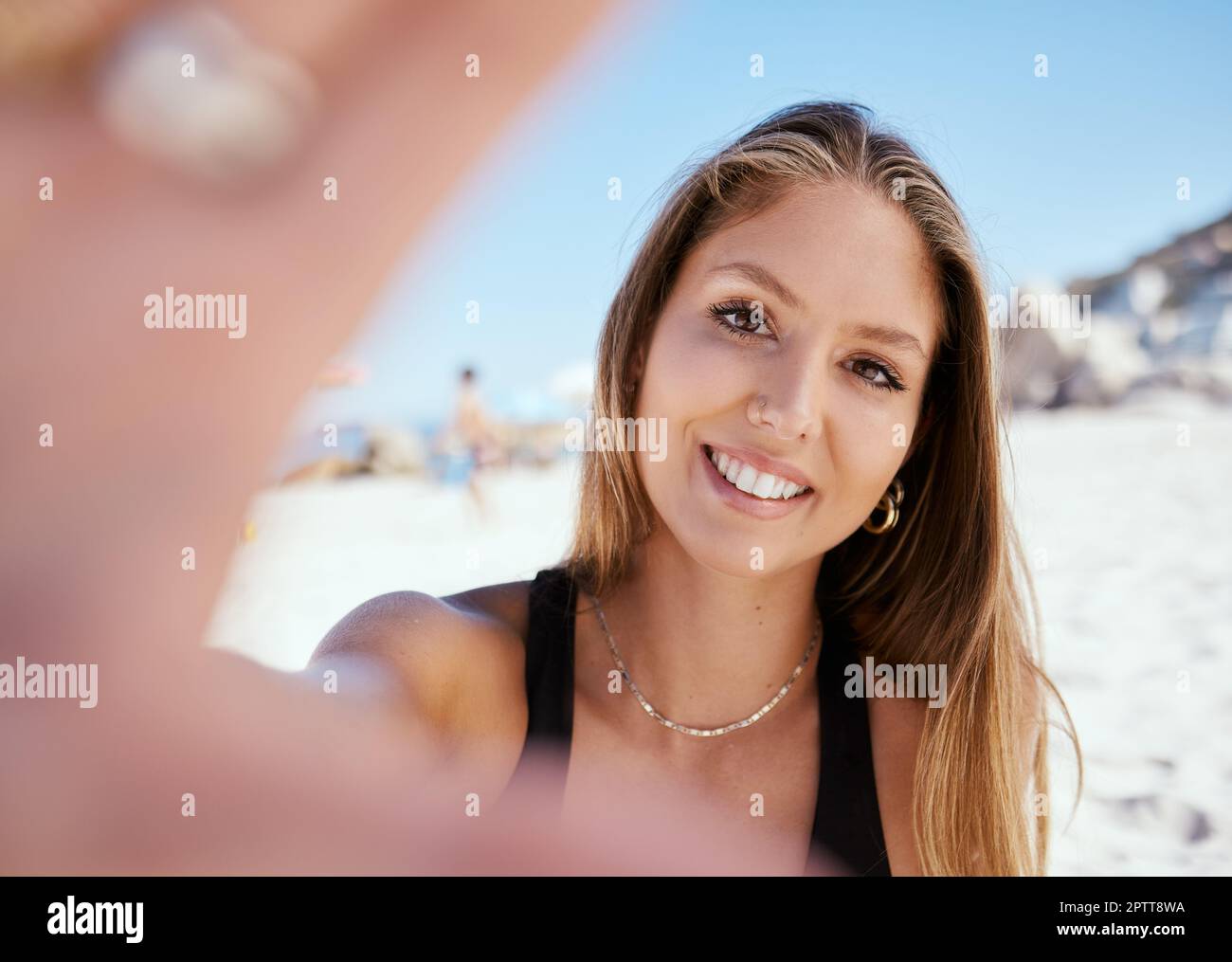 Una bella giovane donna caucasica che si rilassa e scatta una foto al selfie mentre si siede sulla spiaggia. Godetevi una vacanza estiva o una vacanza all'aperto Foto Stock