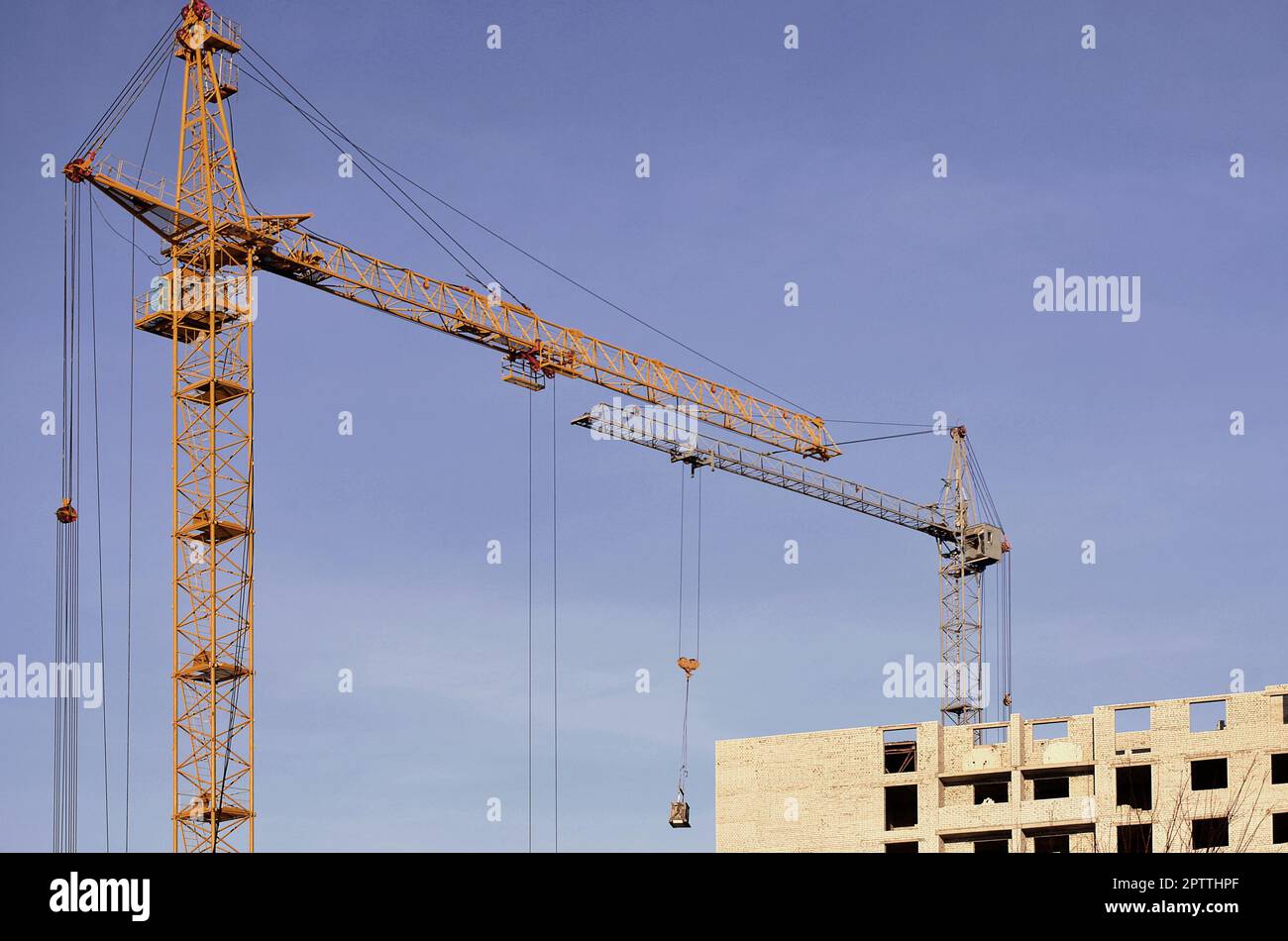 Altezza di lavoro gru interno posto per con alti edifici in costruzione contro un cielo blu chiaro. Gru e costruire il progresso di lavoro con copyspa Foto Stock