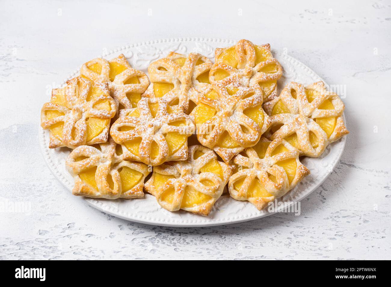 Ananas al forno in pasta sfoglia cosparsa di zucchero a velo su sfondo azzurro, vista dall'alto. Deliziosi budini fatti in casa Foto Stock