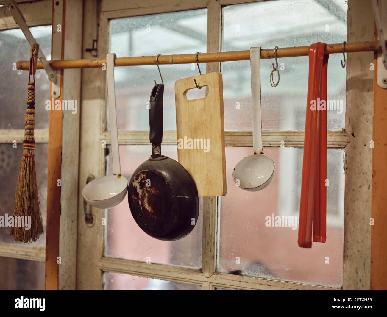 Vecchi utensili da cucina appesi al bar. Dimensioni diverse di pentole e stoviglie sul muro, decorazione casa, sfondo cucina. Foto Stock