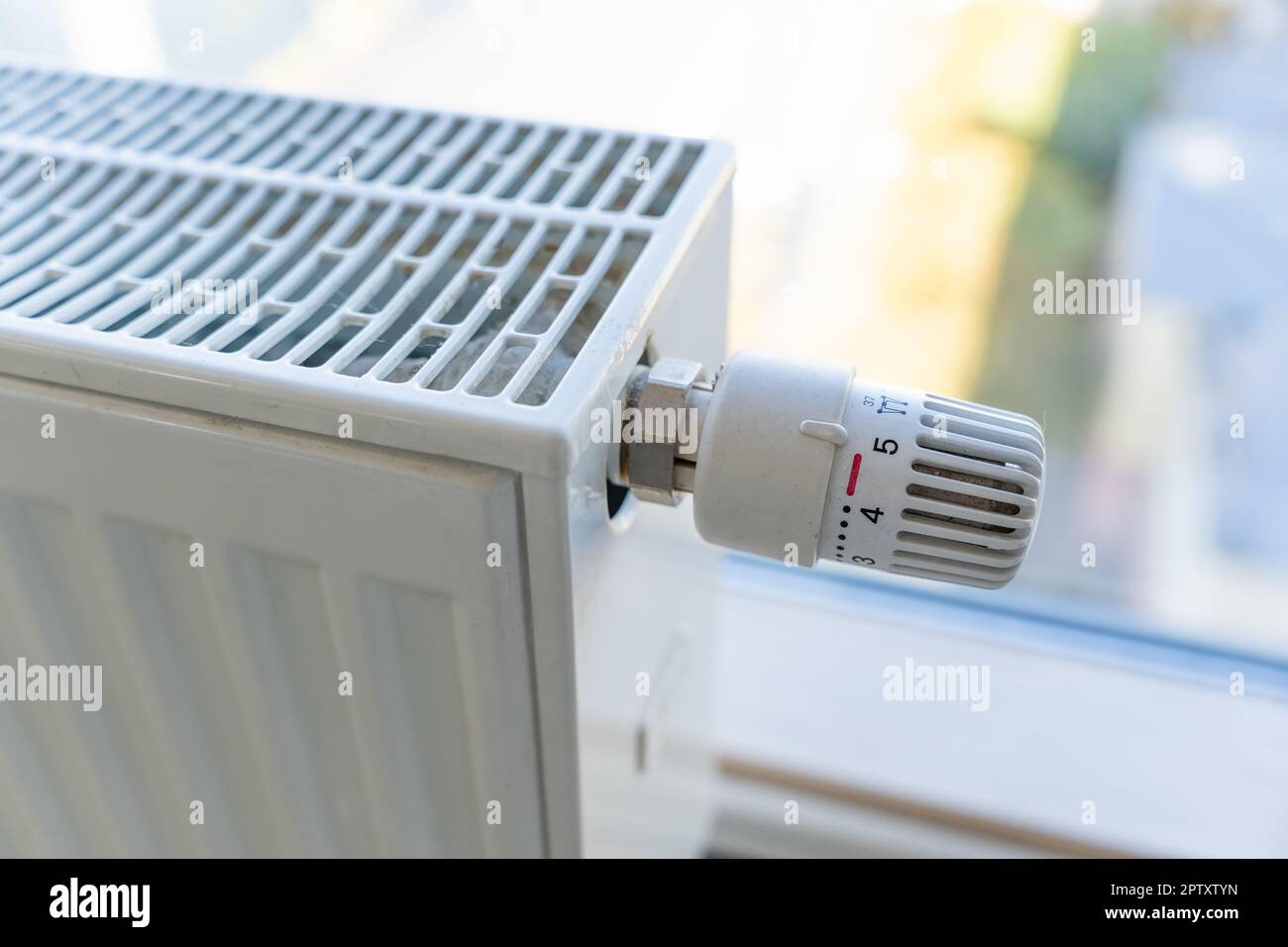 Radiatore di riscaldamento con manopola di regolazione impostata sul valore massimo a causa della brina e della bassa temperatura. Prezzi elevati per il calore e le utenze. Foto Stock