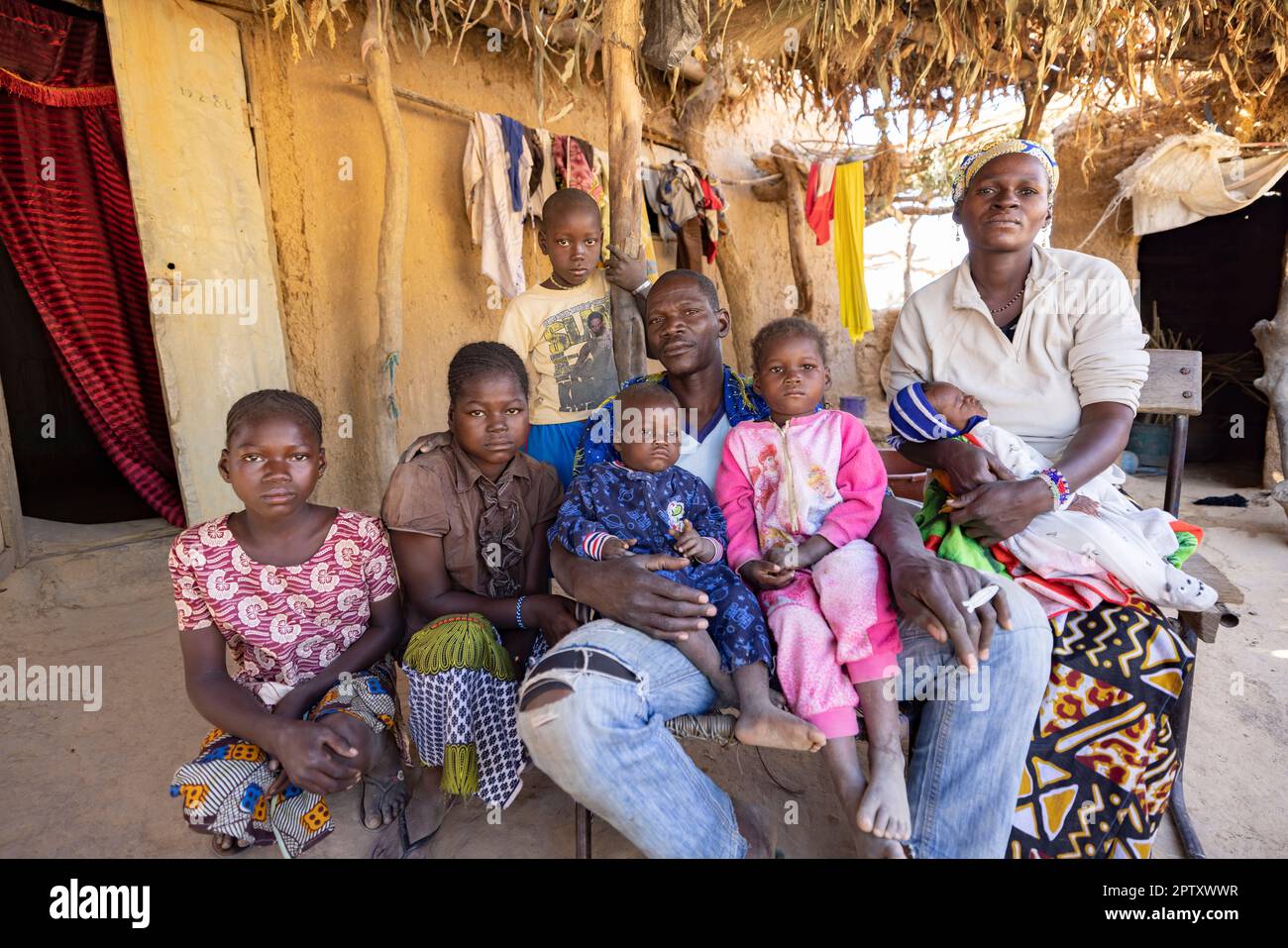 Una grande famiglia seduta insieme di fronte alla propria casa nella regione di Segou, Mali, Africa occidentale. 2022 siccità del Mali e crisi della fame. Foto Stock