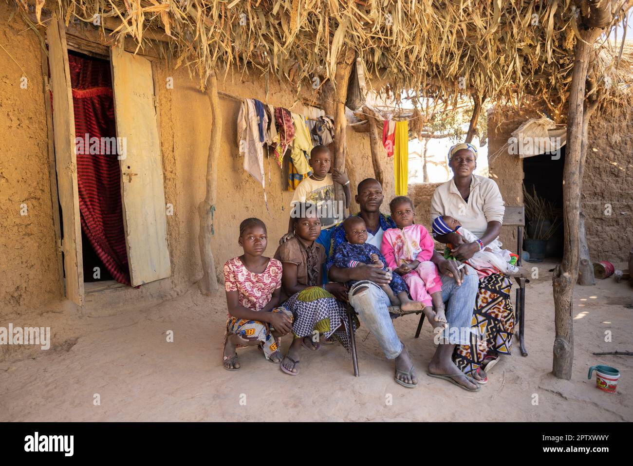 Una grande famiglia seduta insieme di fronte alla propria casa nella regione di Segou, Mali, Africa occidentale. 2022 siccità del Mali e crisi della fame. Foto Stock
