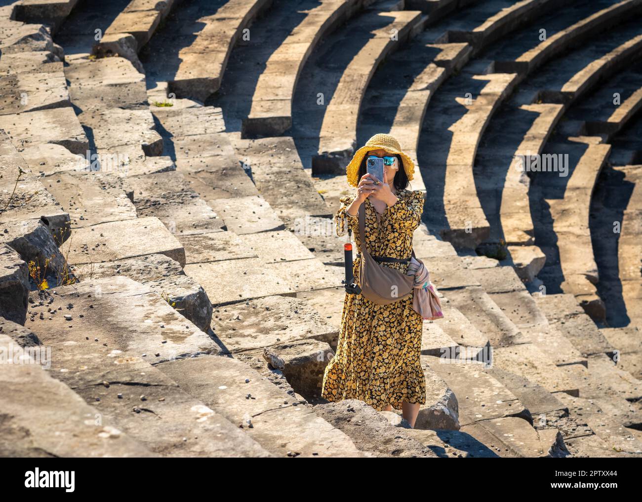 Una donna turista asiatico vietnamita scatta una foto sul suo cellulare mentre visita il grande anfiteatro romano a lato nella provincia di Antalya, Turchia ( Foto Stock