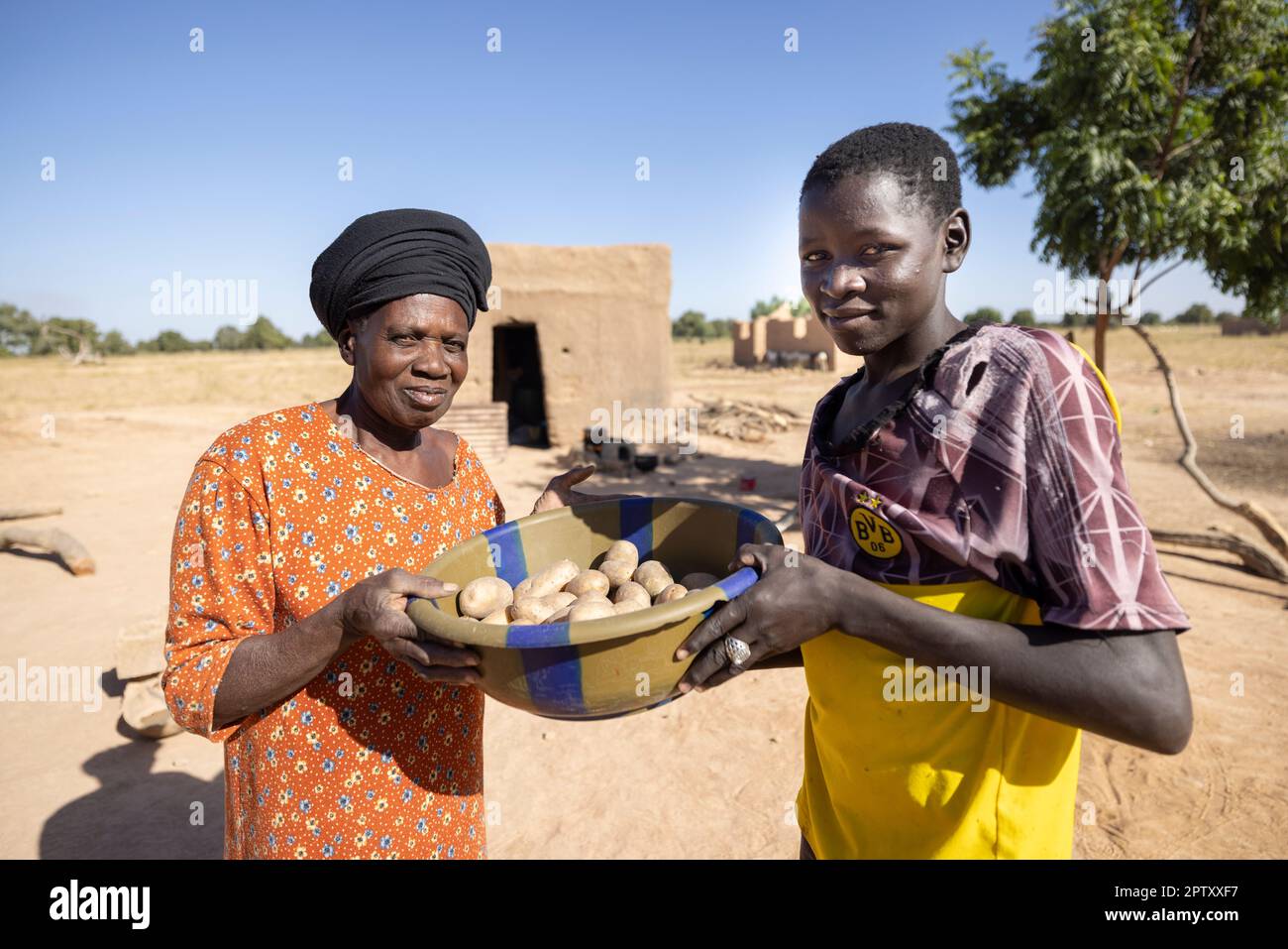 Un giovane uomo condivide un bacino di patate con una donna anziana vicina nella regione di Segou, Mali, Africa occidentale. 2022 siccità del Mali e crisi della fame. Foto Stock