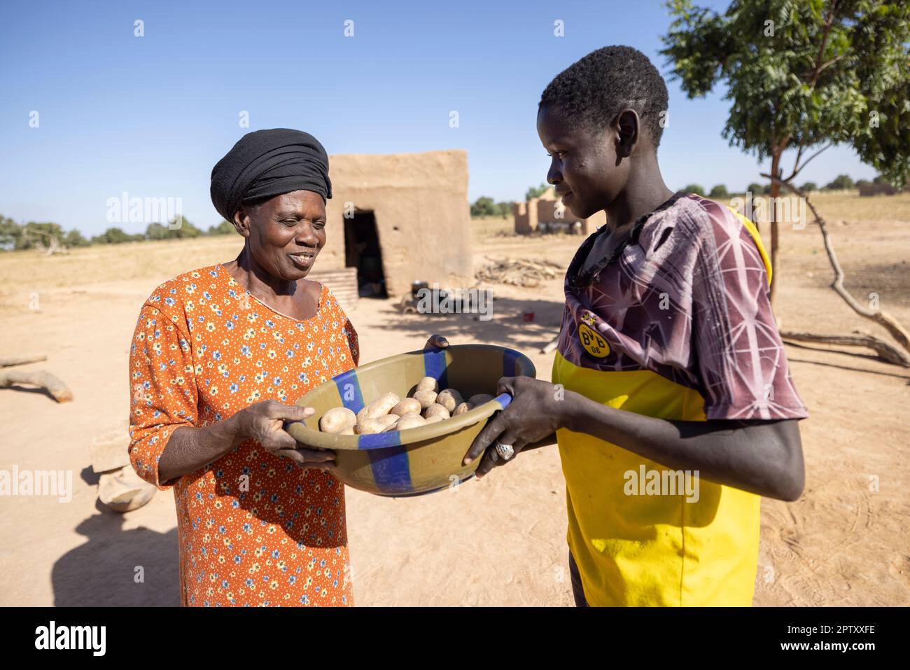 Un giovane uomo condivide un bacino di patate con una donna anziana vicina nella regione di Segou, Mali, Africa occidentale. 2022 siccità del Mali e crisi della fame. Foto Stock