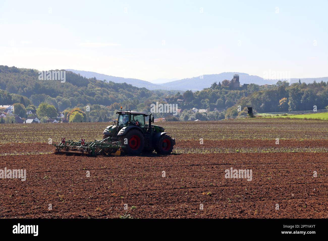 Landwirt eggt das Feld, im Hintergrund Burg Trendelburg, Hessen, Deutschland Foto Stock
