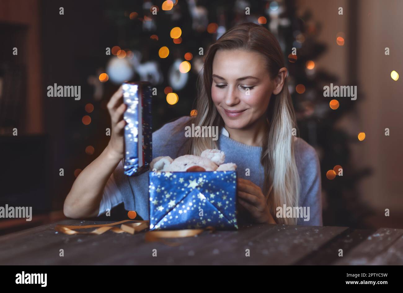 Ritratto di una ragazza felice godendo regali a casa la vigilia di Natale. Decorato Xmas Bokeh albero sfondo. Felice Anno Nuovo. Vacanze invernali Foto Stock