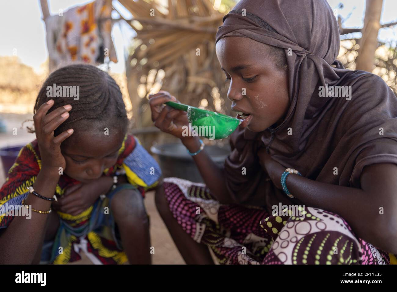 Una ragazza mangia un pasto di porridge di miglio nella regione di Segou, Mali, Africa occidentale. 2022 siccità del Mali e crisi della fame. Foto Stock