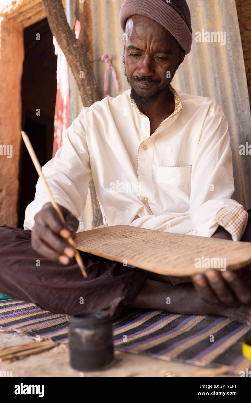 Un uomo IDP pratica la calligrafia islamica nella regione di Segou, Mali, Africa occidentale. 2022 siccità del Mali e crisi della fame. Foto Stock