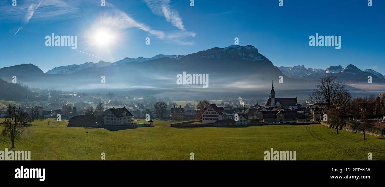 Foto panoramica del villaggio di Schwyz nel cantone omonimo in Svizzera alla luce del sole con nuvole di nebbia Foto Stock