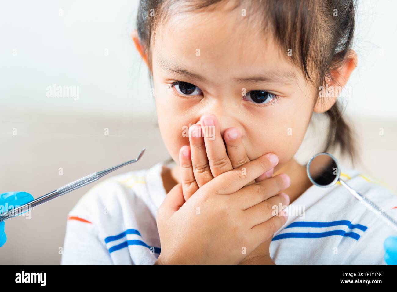 Esame dentale del bambino. Il medico esamina la cavità orale del bambino usa lo specchio della bocca per controllare la cavità dei denti ma la bocca della copertura della bambina non ha bisogno di controllare s Foto Stock