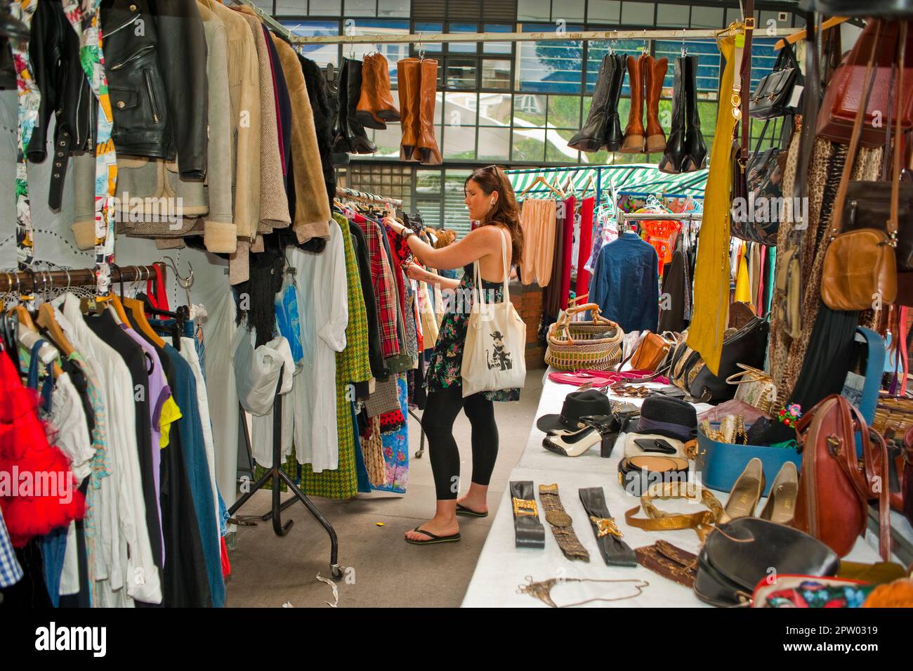 Londra, Regno Unito, giovane donna con borsa in un negozio di moda, shopping nel mercato locale delle pulci, negozio di abbigliamento usato, vista grandangolare Foto Stock