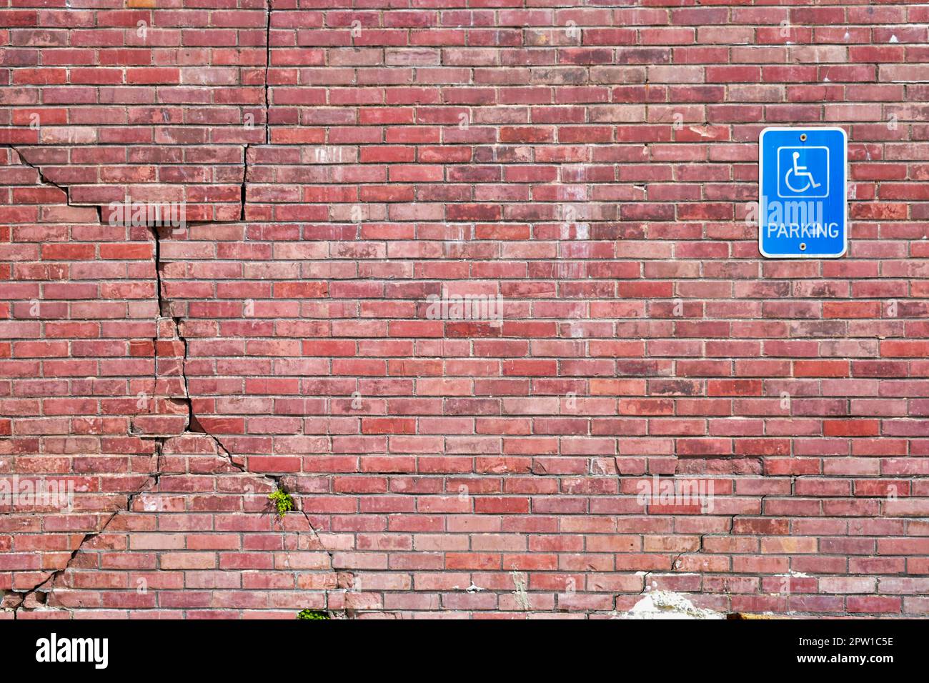 Cartello di parcheggio per disabili su pareti in mattoni spaccati Foto Stock