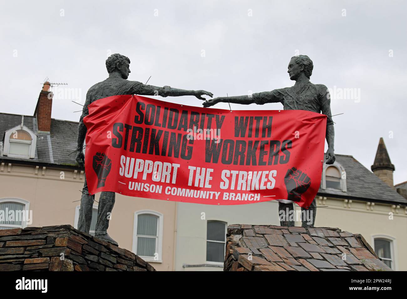Banner sindacale drappeggiato tra le mani attraverso la scultura divide in Derry Foto Stock