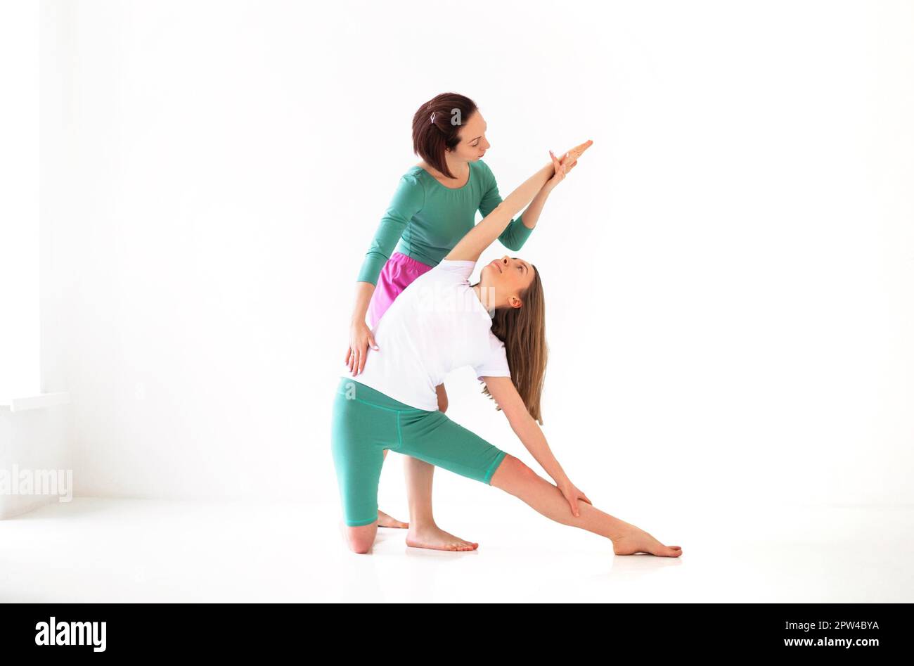Donna adulta che aiuta la donna nello sport con fare yoga posa e stendendo i bracci Foto Stock