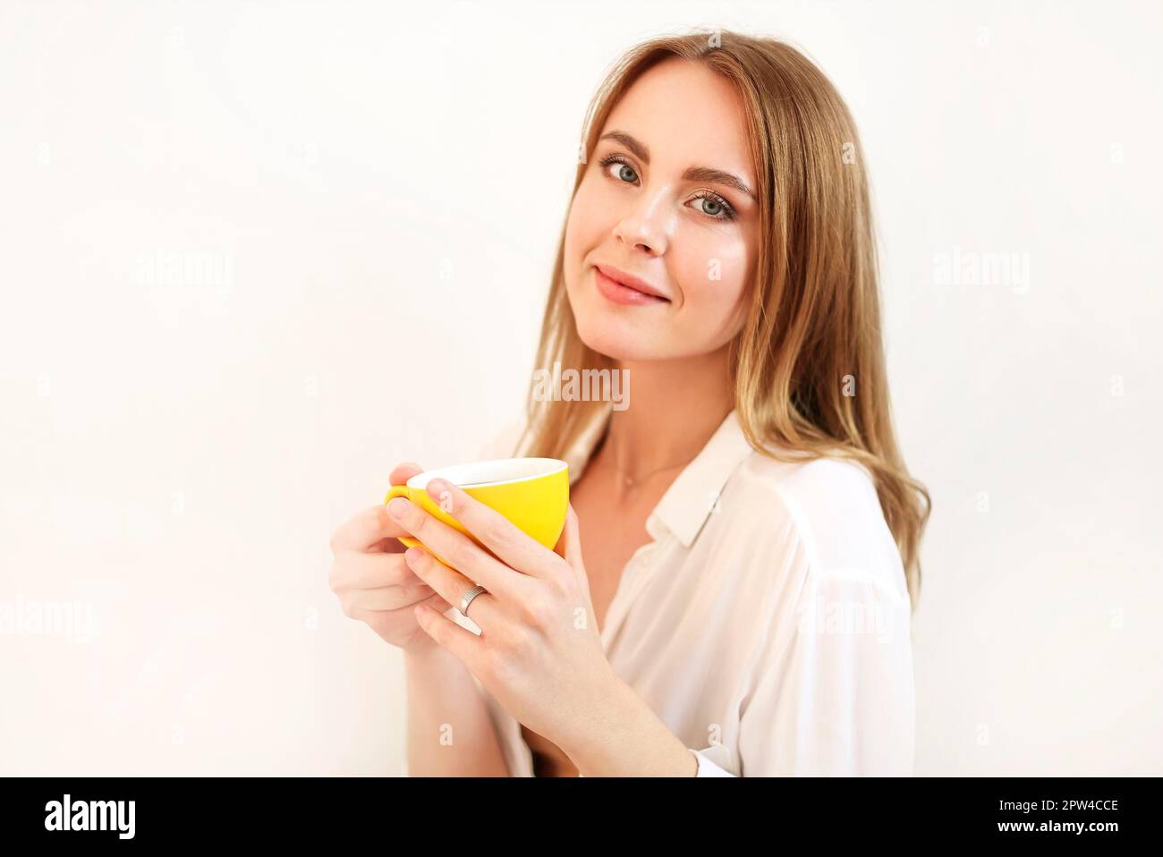Donna adulta in occhi di chiusura accappatoio mentre ha una tazza di caffè nero aromatico appena preparato Foto Stock