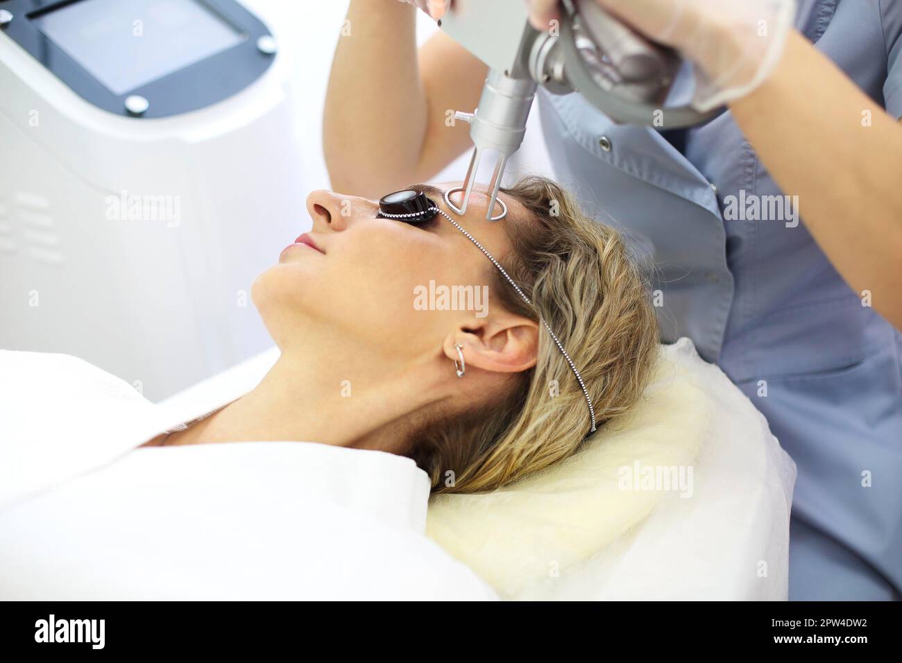 Tecnico laser di bellezza che esegue una sessione cosmetica di resurfacing della pelle su una paziente femminile, anche chiamata una buccia laser o fotofacciale Foto Stock