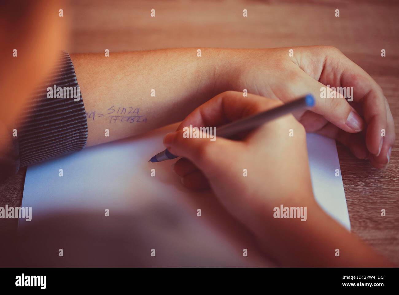 Cropped shot of student using cheat sheet on math exam, reading written formula on hand while cheating during test in university or school, selective Foto Stock