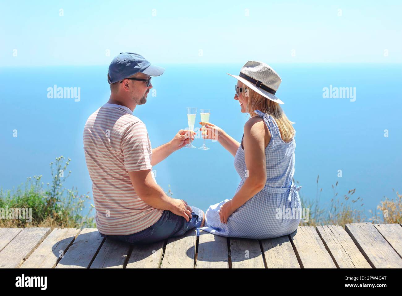 Due bicchieri di champagne nelle mani di un uomo e di una donna. Concetto romantico di viaggio Foto Stock