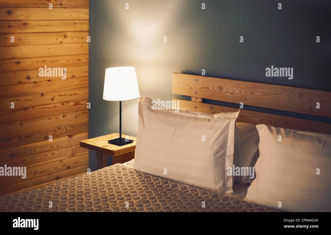Scena notturna in camera accogliente, comodino con lampada. Lampada da camera sul comodino accanto al letto Foto Stock