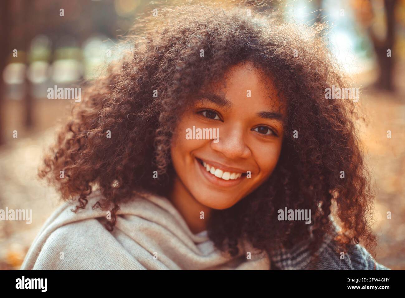 Carino autunno primo piano ritratto di giovane sorridente felice afroamericana con capelli ricci godendo passeggiata nel parco in autunno stagione. Foto all'aperto di Foto Stock