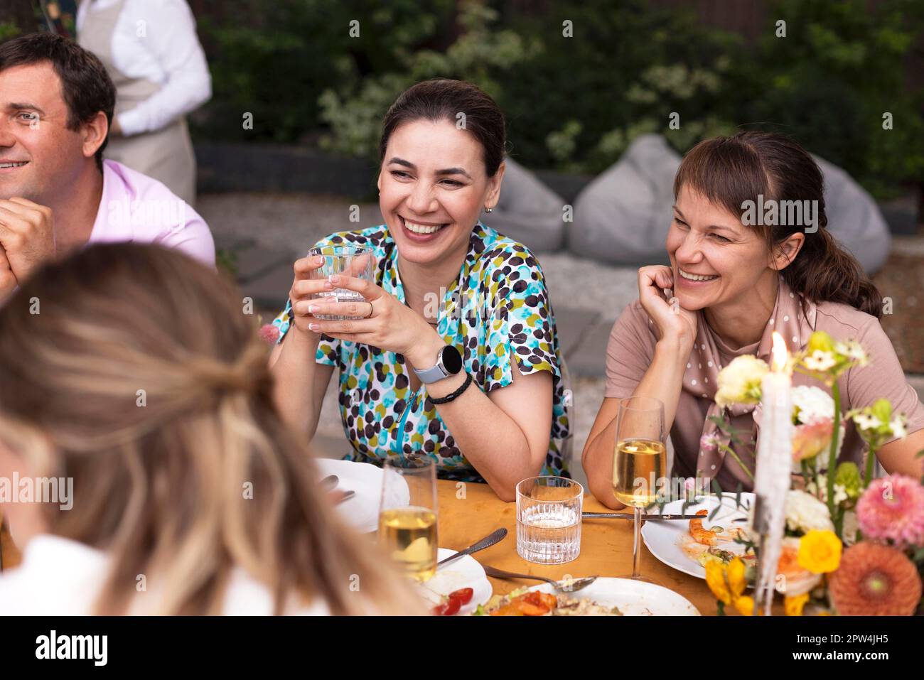 Molta gente che dice i saluti e che mostra i loro calici dello champagne pieni di vino frizzante a vicenda mentre godendo una festa di nozze all'aperto su un Foto Stock