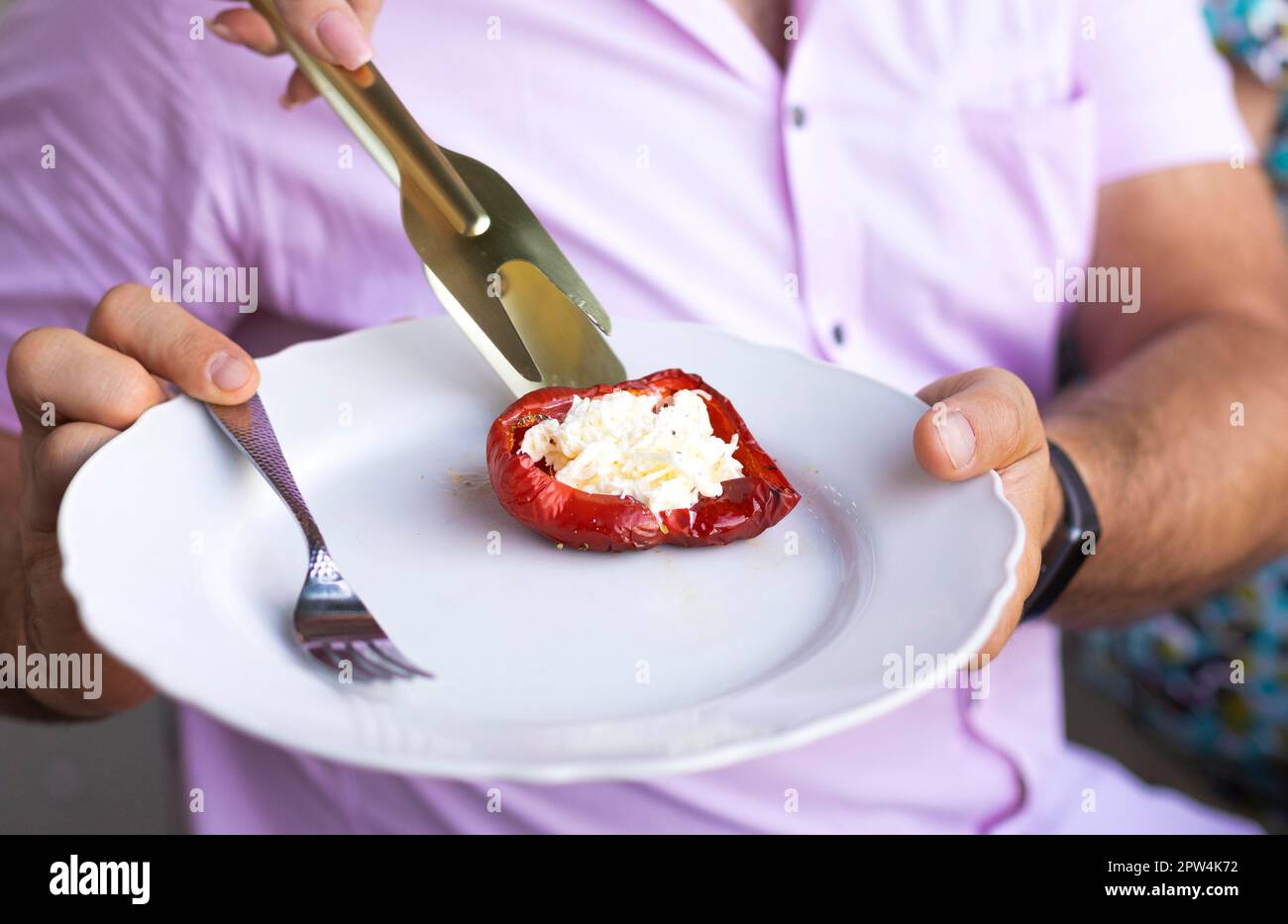 Peperoni rossi al forno ripieni di erbe e formaggio su un piatto durante la festa estiva all'aperto. Piatto vegetariano, verdure ripiene Foto Stock