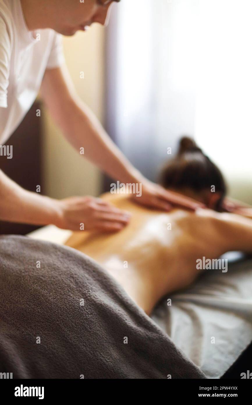 Master maschile che dà massaggio di muscoli della schiena e delle spalle a. donna anonima sdraiata sul tavolo nel salone termale Foto Stock Master maschile che dà massaggio di muscoli della schiena e delle spalle a. donna anonima sdraiata sul tavolo nel salone termale Foto Stock