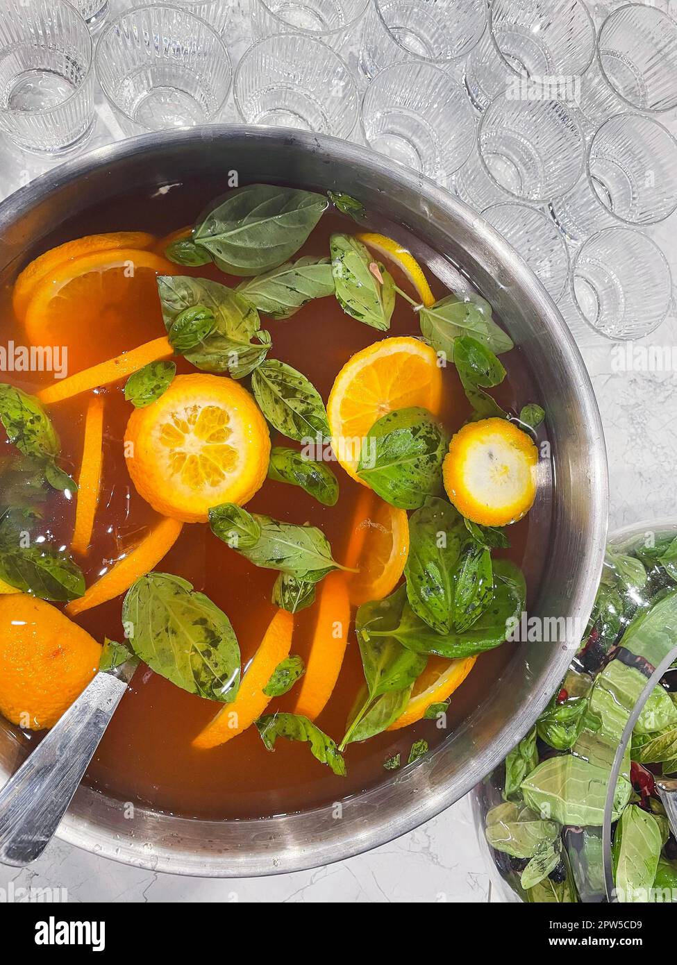 Punch grande ciotola con arance e menta. Succo di agrumi bollito. Bere con una varietà di frutta primo piano. Cocktail alcolico all'arancia. Bicchieri vuoti sul Foto Stock