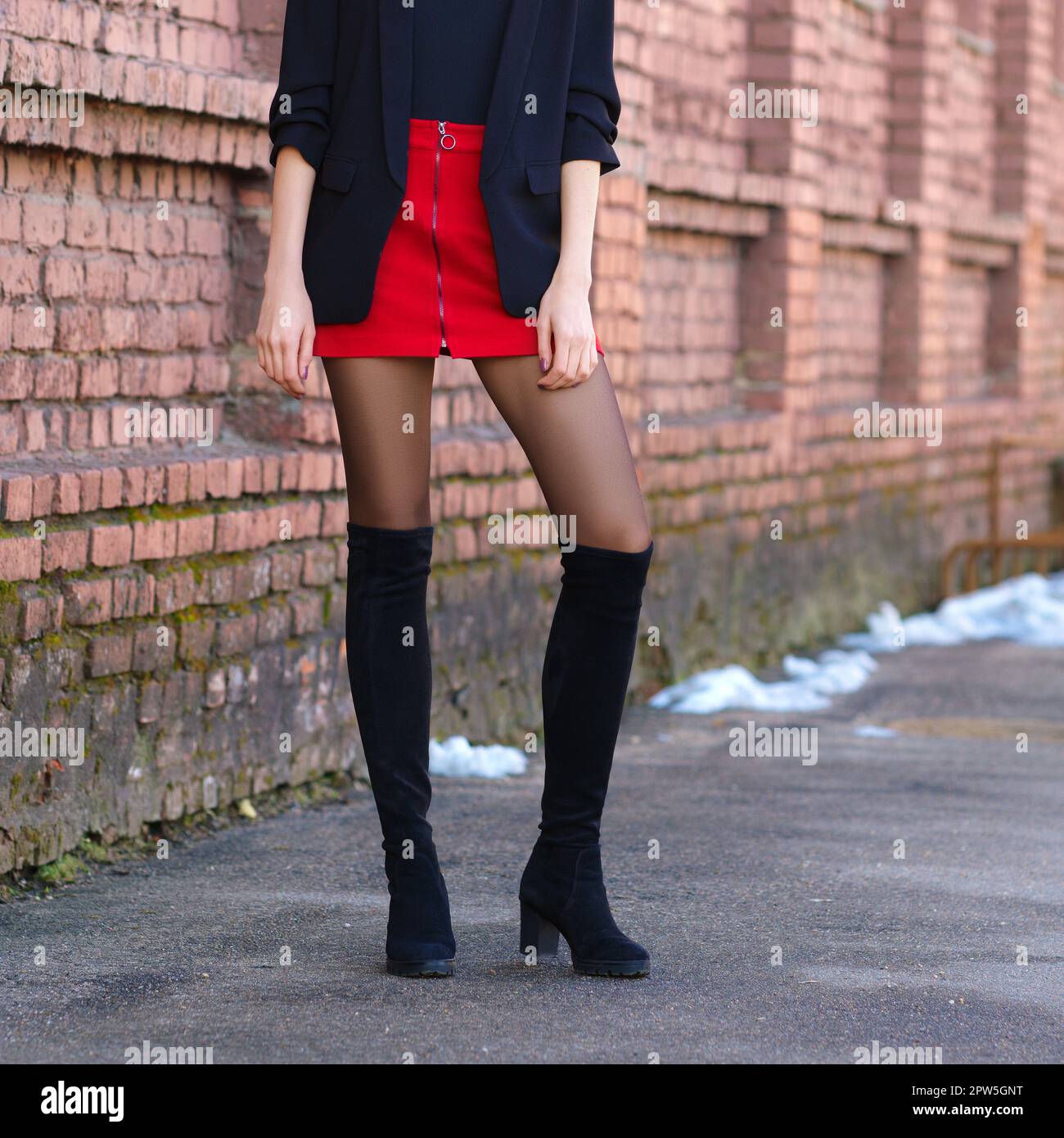 Immagine ritagliata di belle gambe femminili in camoscio nero stivali, mini gonna e giacca in pelle all'aperto. Foto Stock