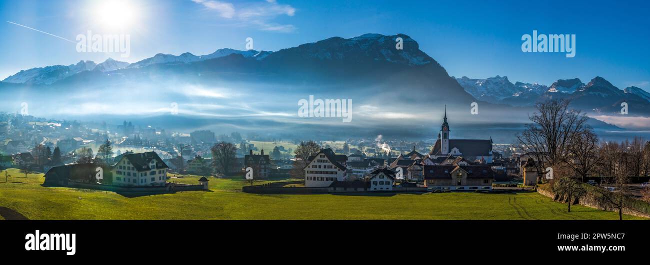 Foto panoramica del villaggio di Schwyz nel cantone omonimo in Svizzera alla luce del sole con nuvole di nebbia Foto Stock