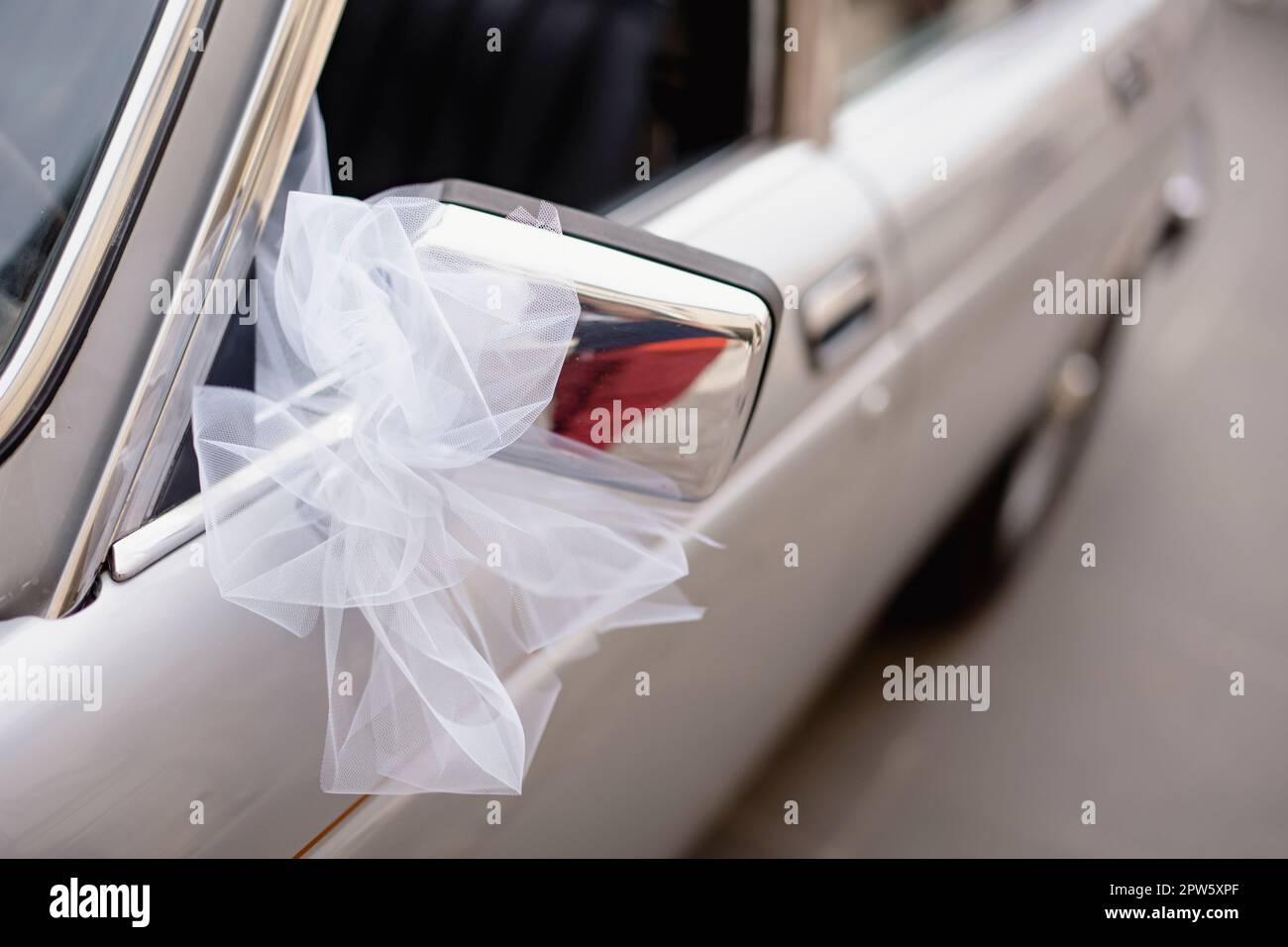 Decorazione di nozze a nastro bianco su uno specchio laterale d'auto d'epoca. Foto Stock