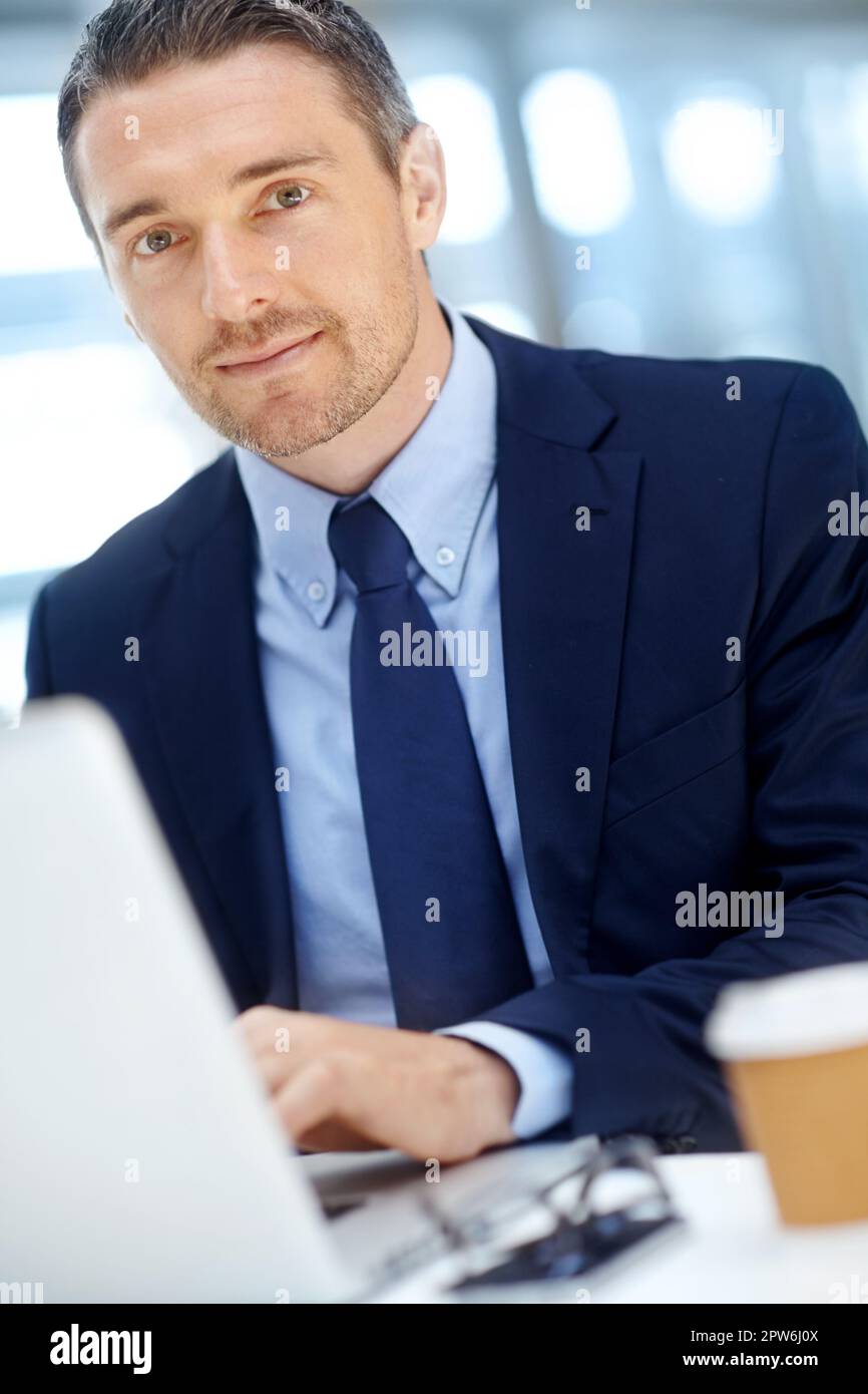 HES un esperto negli affari aziendali. Bell'uomo d'affari maturo che usa il suo computer portatile seduto alla sua scrivania Foto Stock