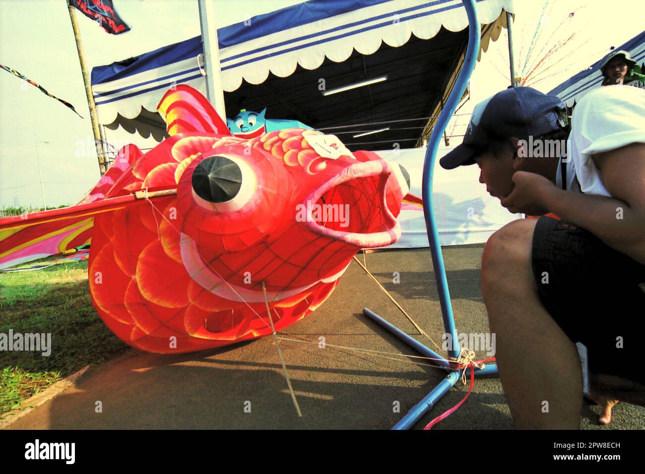 Un uomo sta prestando attenzione ad un aquilone tridimensionale creato sotto forma di pesce durante il Festival Internazionale del aquilone di Giacarta del 2004 che si è tenuto il 9-11 luglio a Karnaval (Carnival) Beach ad Ancol Dreamland, a nord di Giacarta, in Indonesia. Foto Stock