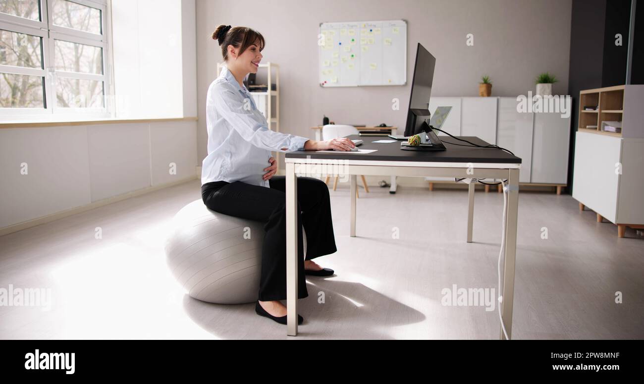 Donna incinta in ufficio. Postura della scrivania e gravidanza Foto Stock