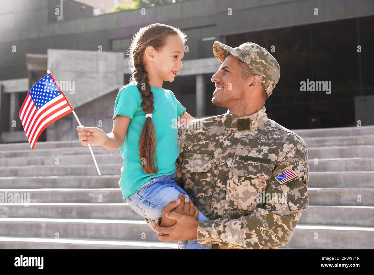 Soldato e sua figlia con bandiera americana all'aperto. Veterans Day negli Stati Uniti Foto Stock