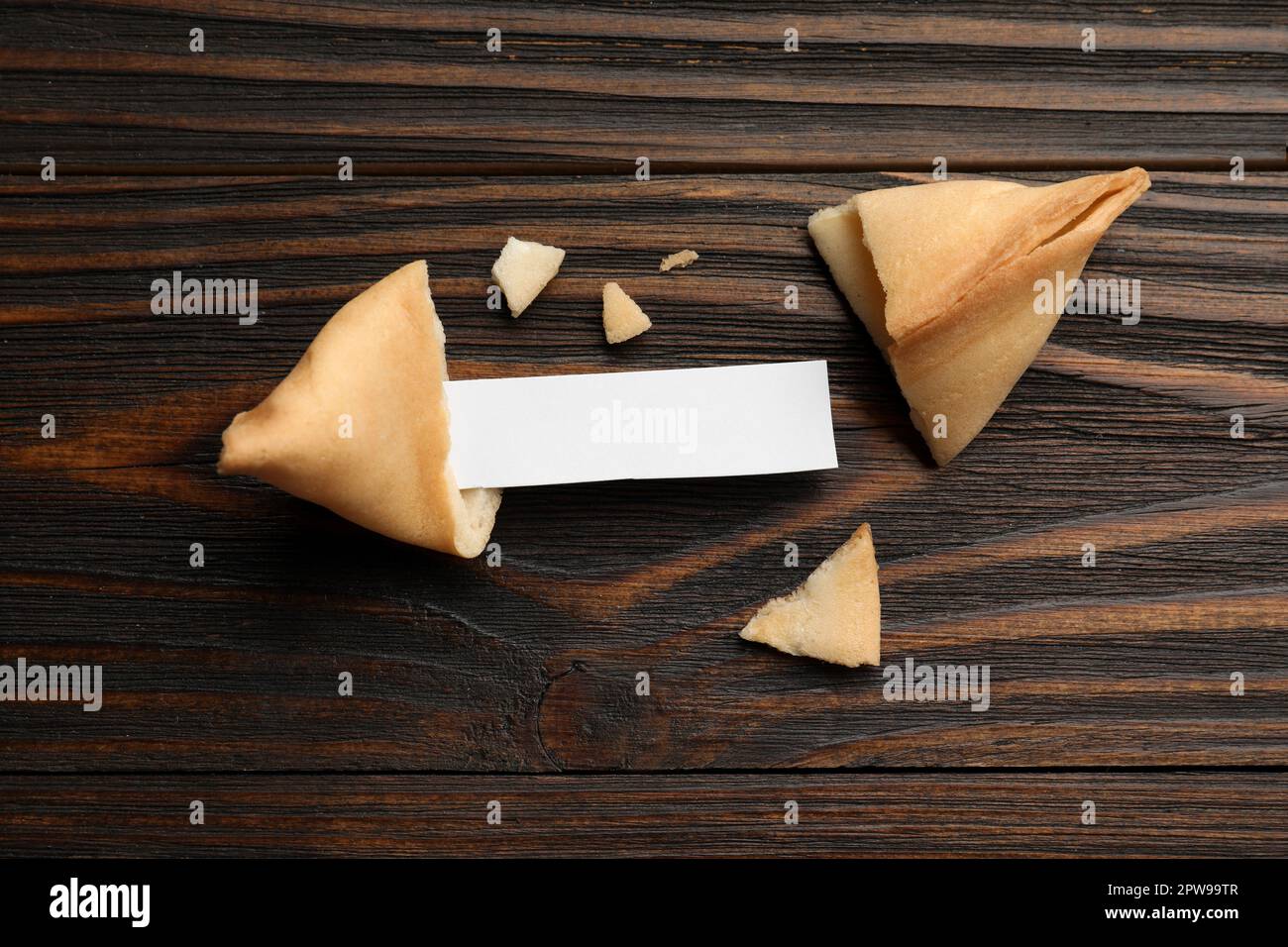 Biscotti e carta gustosi della fortuna con predizione su tavolo di legno, piatto. Spazio per il testo Foto Stock