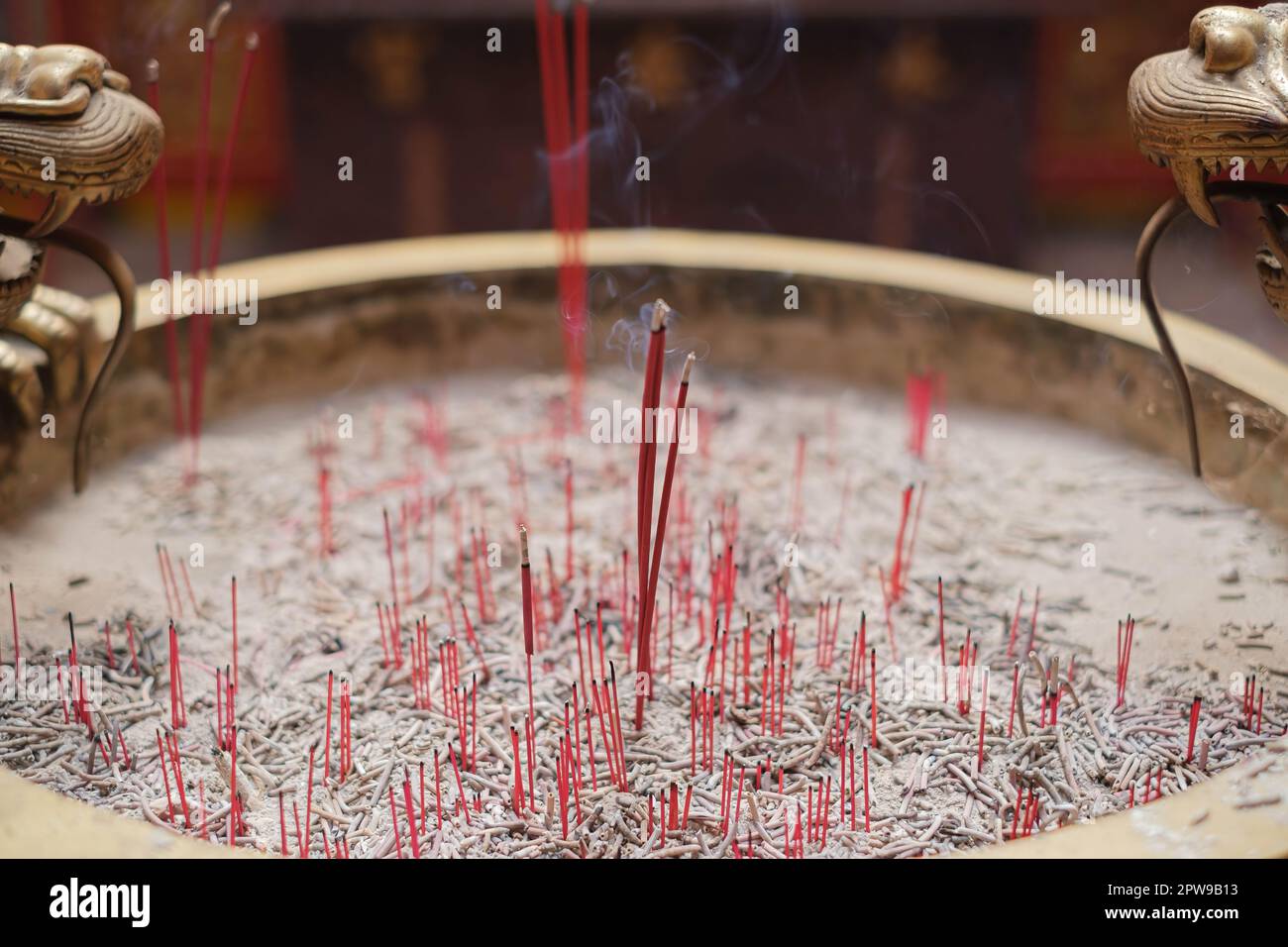 Primo piano di una ciotola di incenso con diversi bastoncini bruciati all'interno. Il fumo dai bastoncini di incenso sta aumentando e creando un'atmosfera nebulosa. Foto Stock