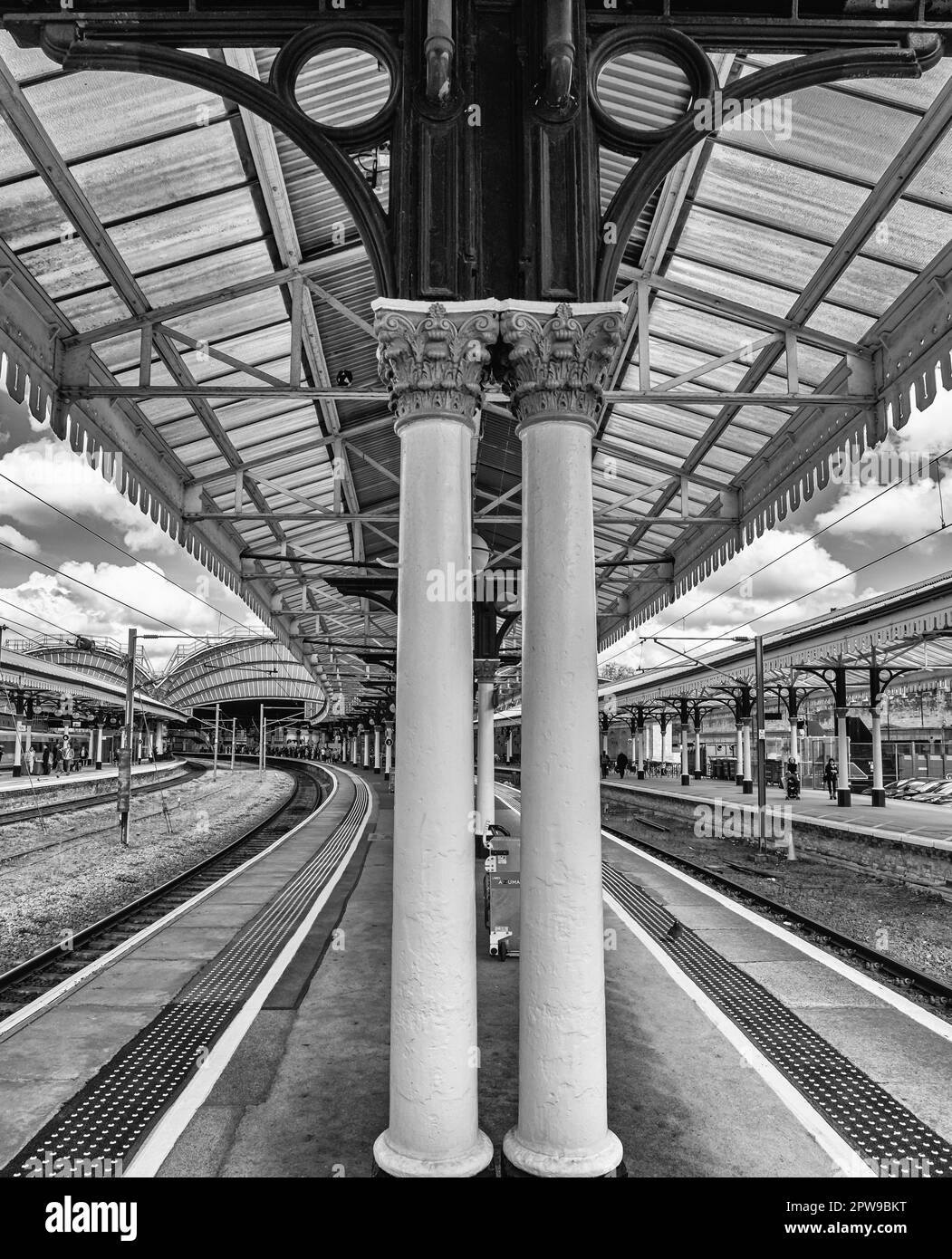 Due colonne sostengono un baldacchino del 19th ° secolo come curva verso un arco e l'ingresso alla stazione ferroviaria principale. Un cielo con nuvola è sopra. Foto Stock