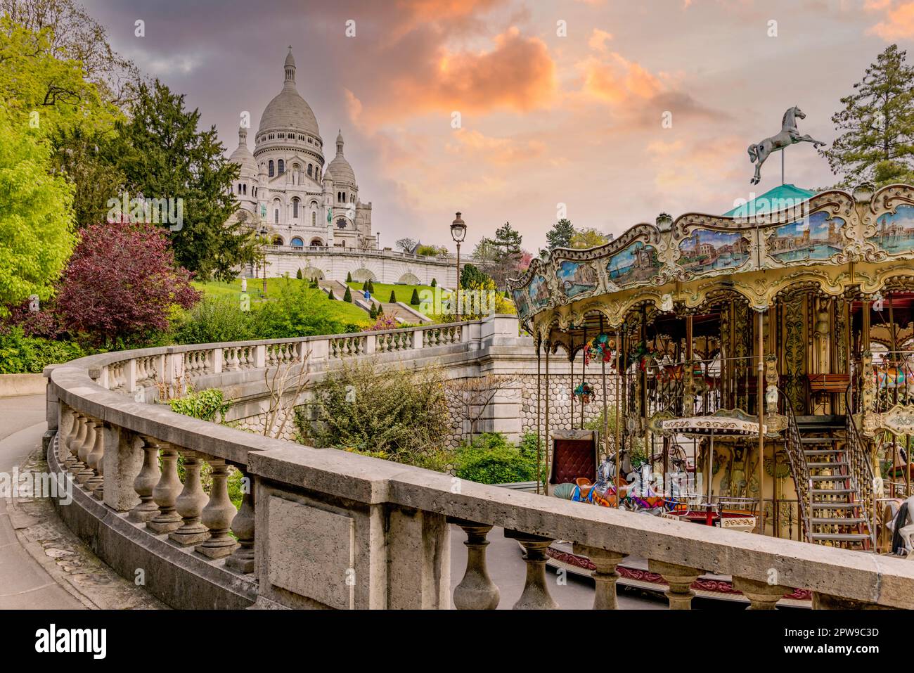Carosello e giardini formali sotto il Sacré-Cœur a Parigi, che creano un'attrazione familiare colorata nella storica Montmartre. Foto Stock